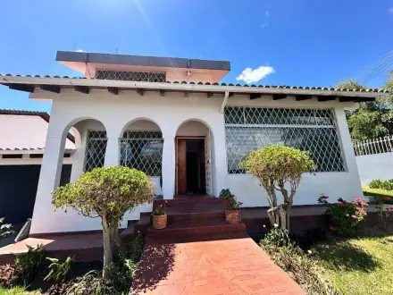 Fachada con arcos y jardín frontal de la casa en Cumbayá